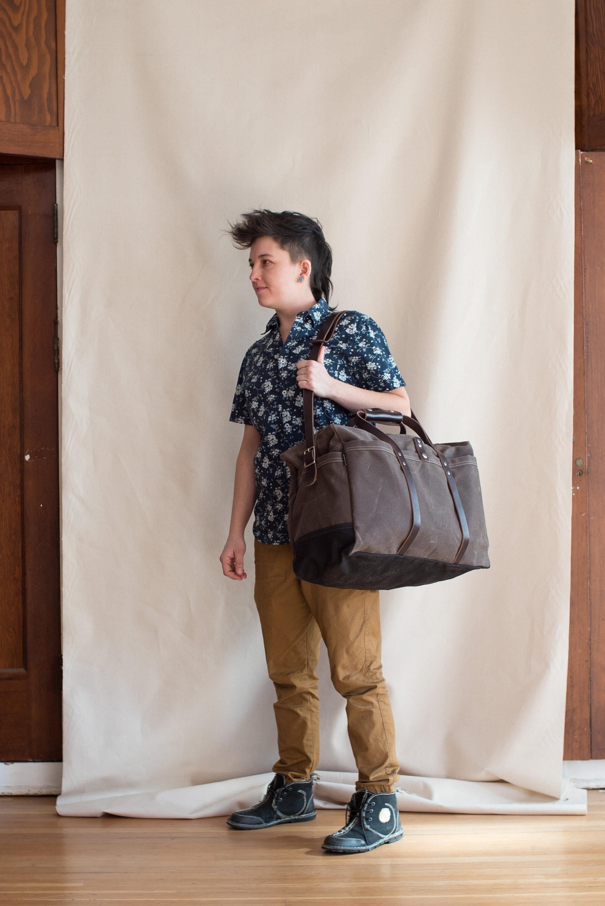 Model Holding Carry-on Duffel in Slate with dark brown leather. 