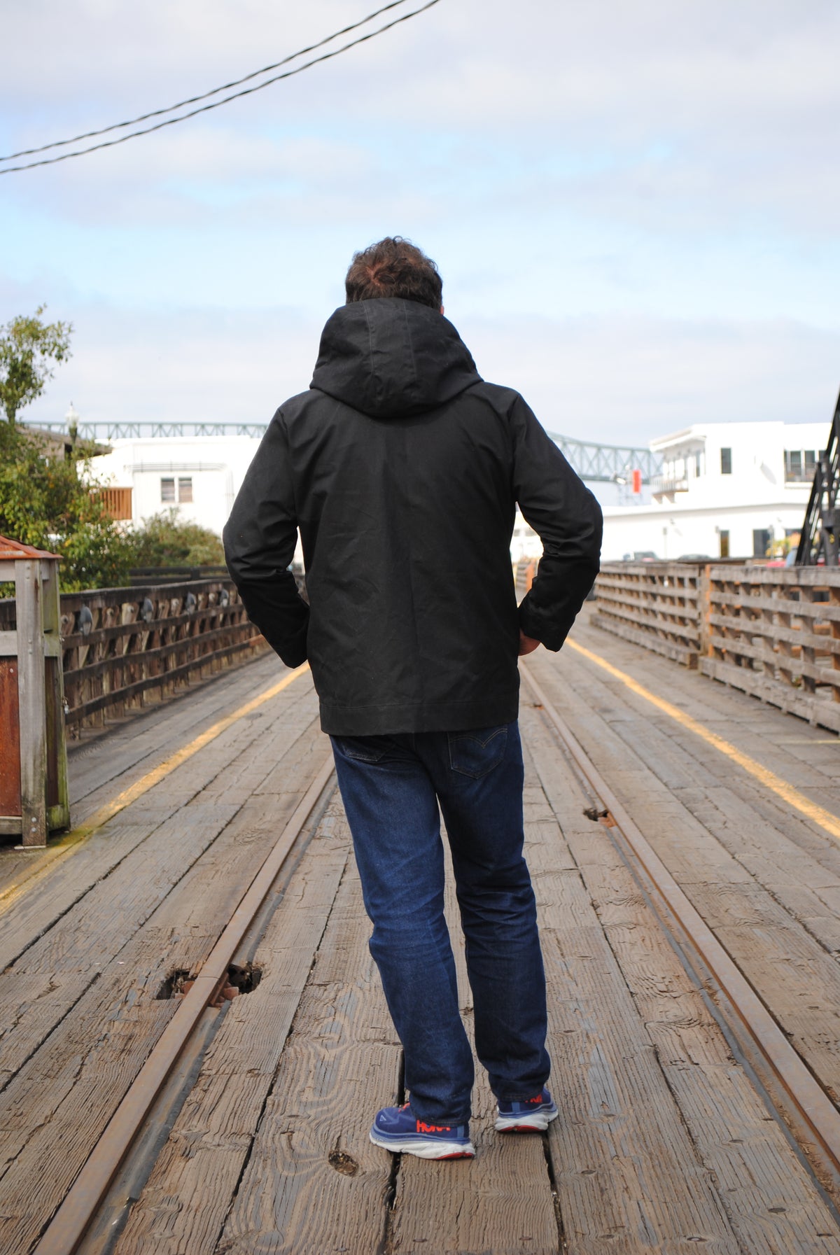 Back view of model wearing black waxed canvas rain jacket
