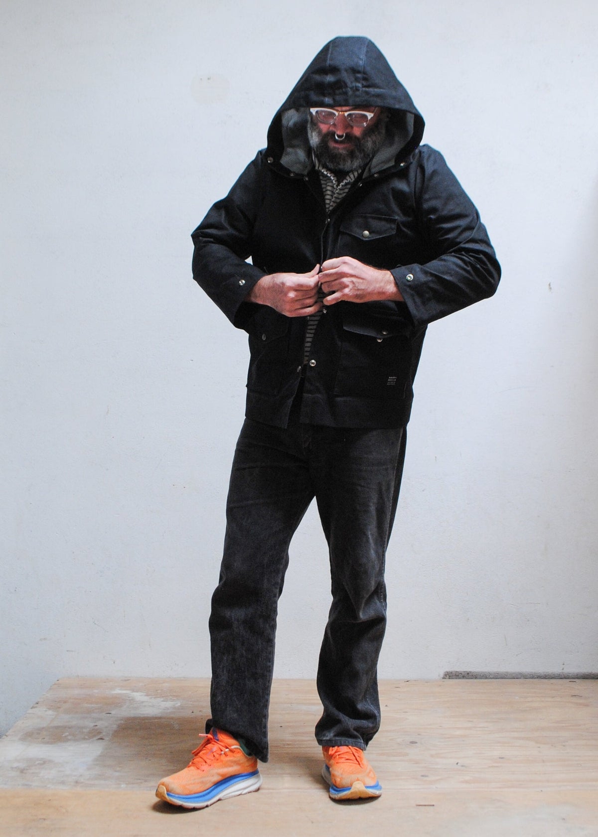 Model buttoning up black waxed canvas rain jacket