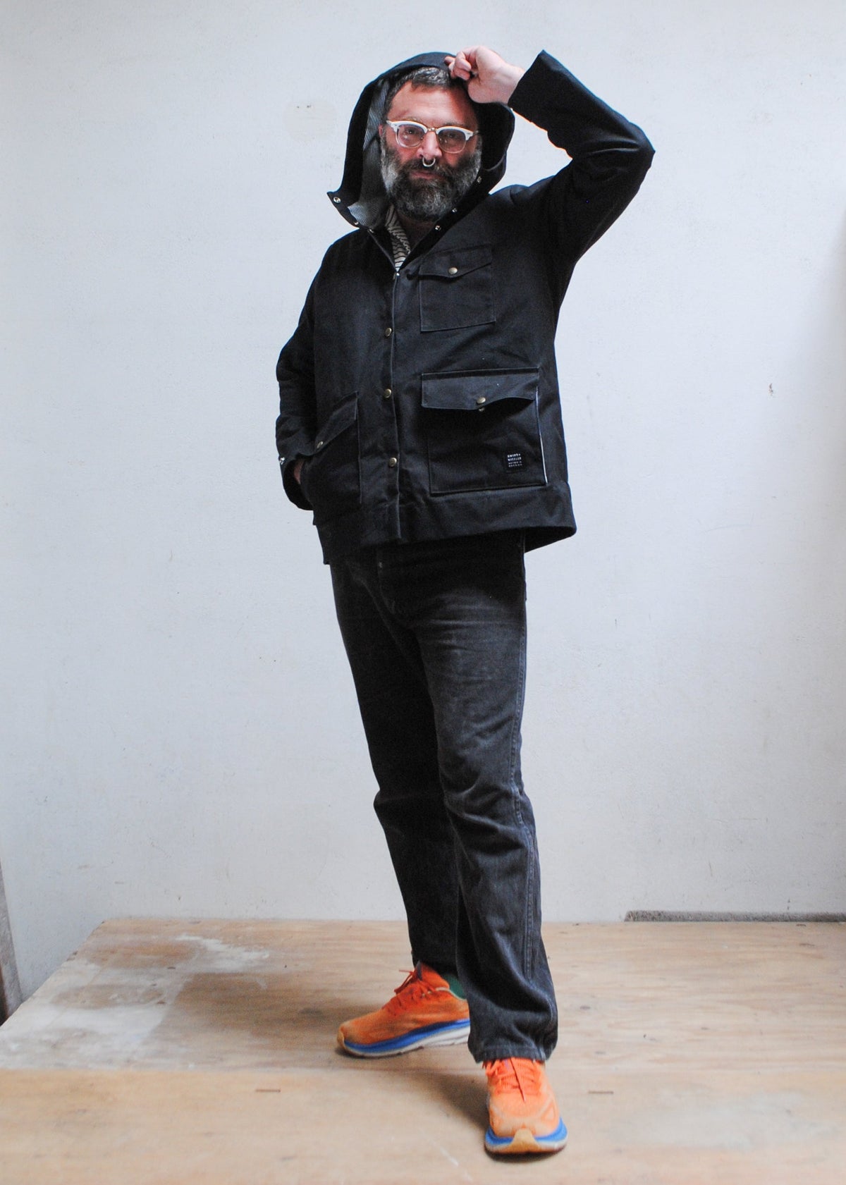 Model wearing black waxed canvas rain jacket with hood up