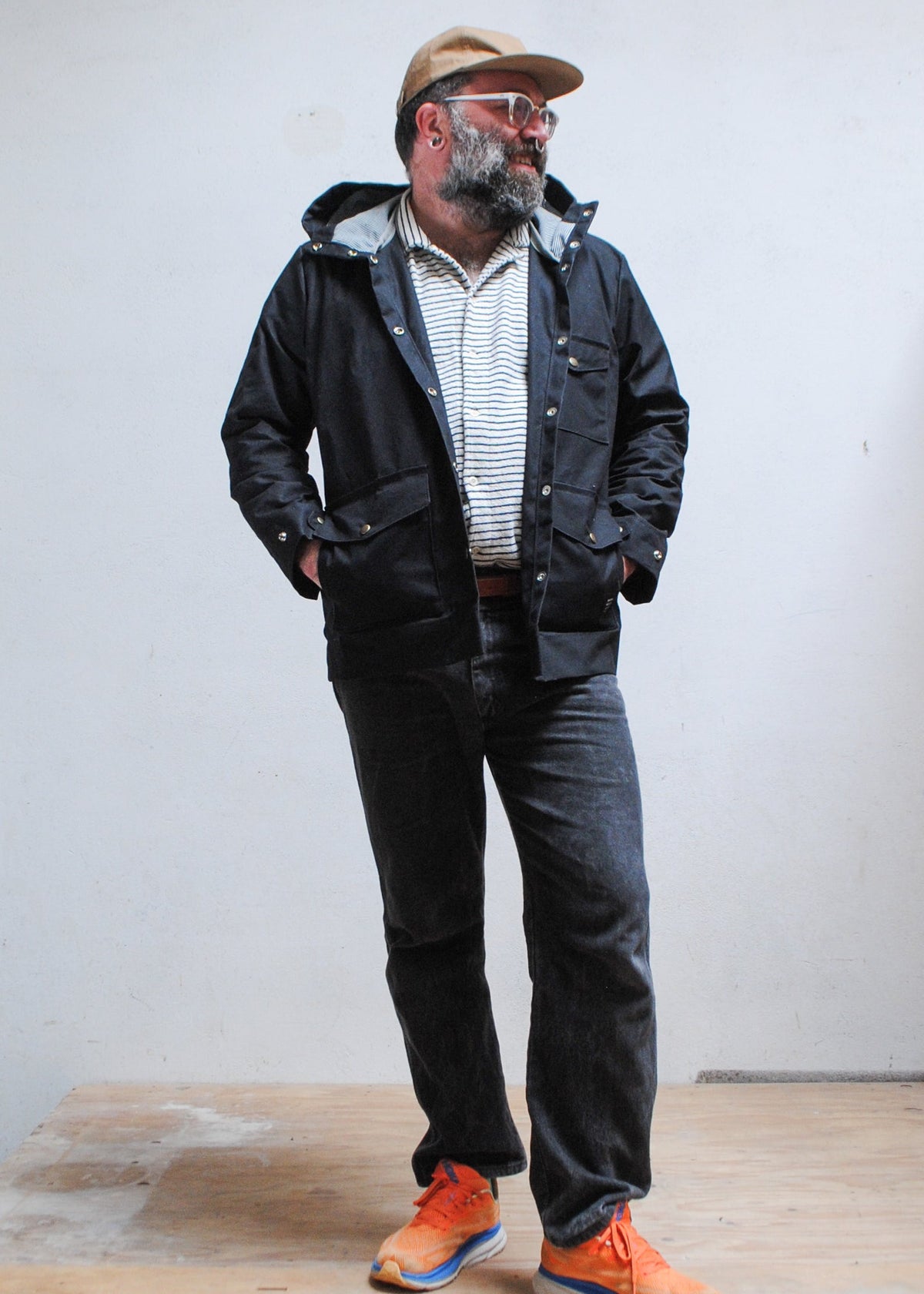 Model wearing black waxed canvas rain jacket with hands tucked into waist pockets