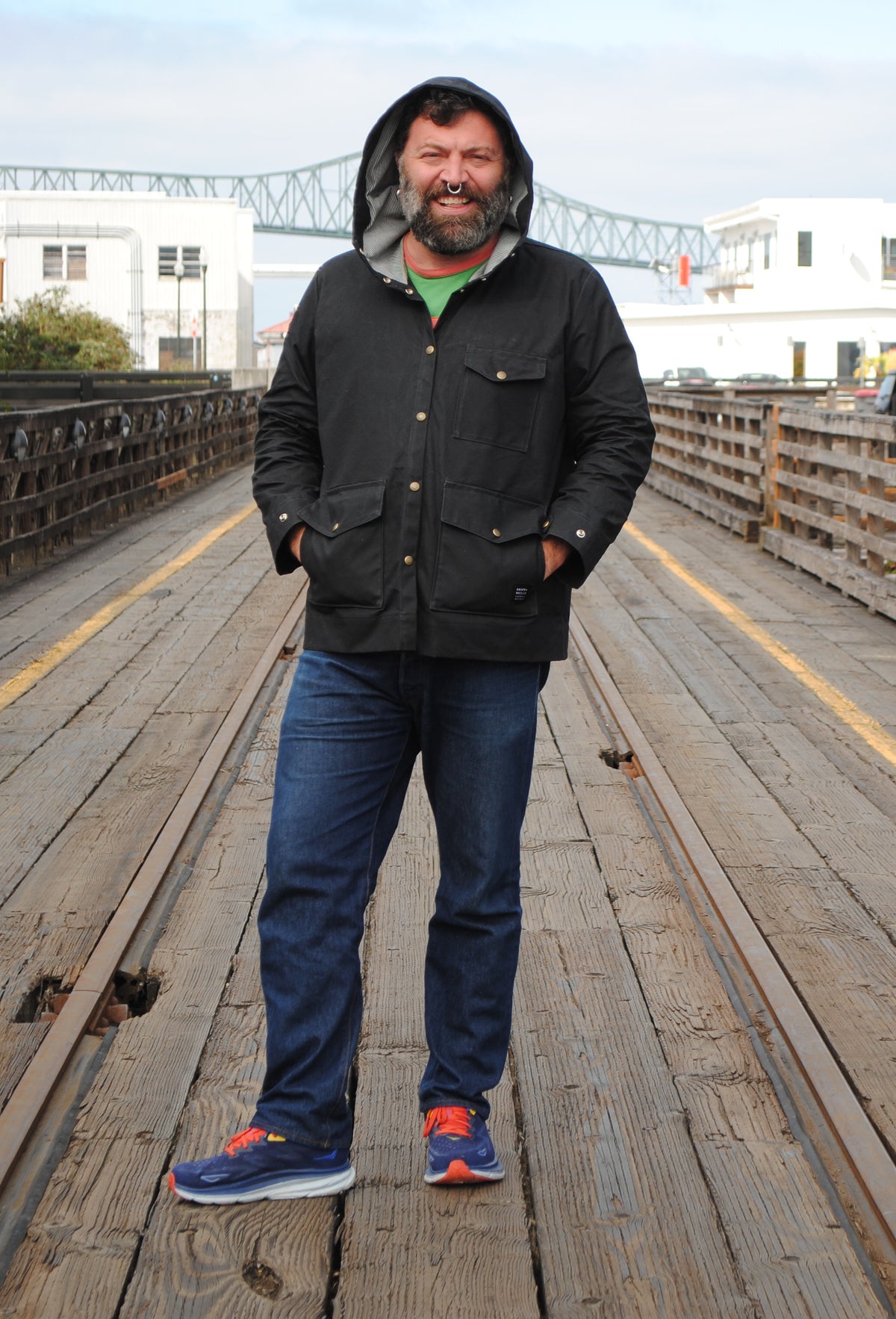 Model wearing black waxed canvas rain jacket with hands in jacket's waist pockets