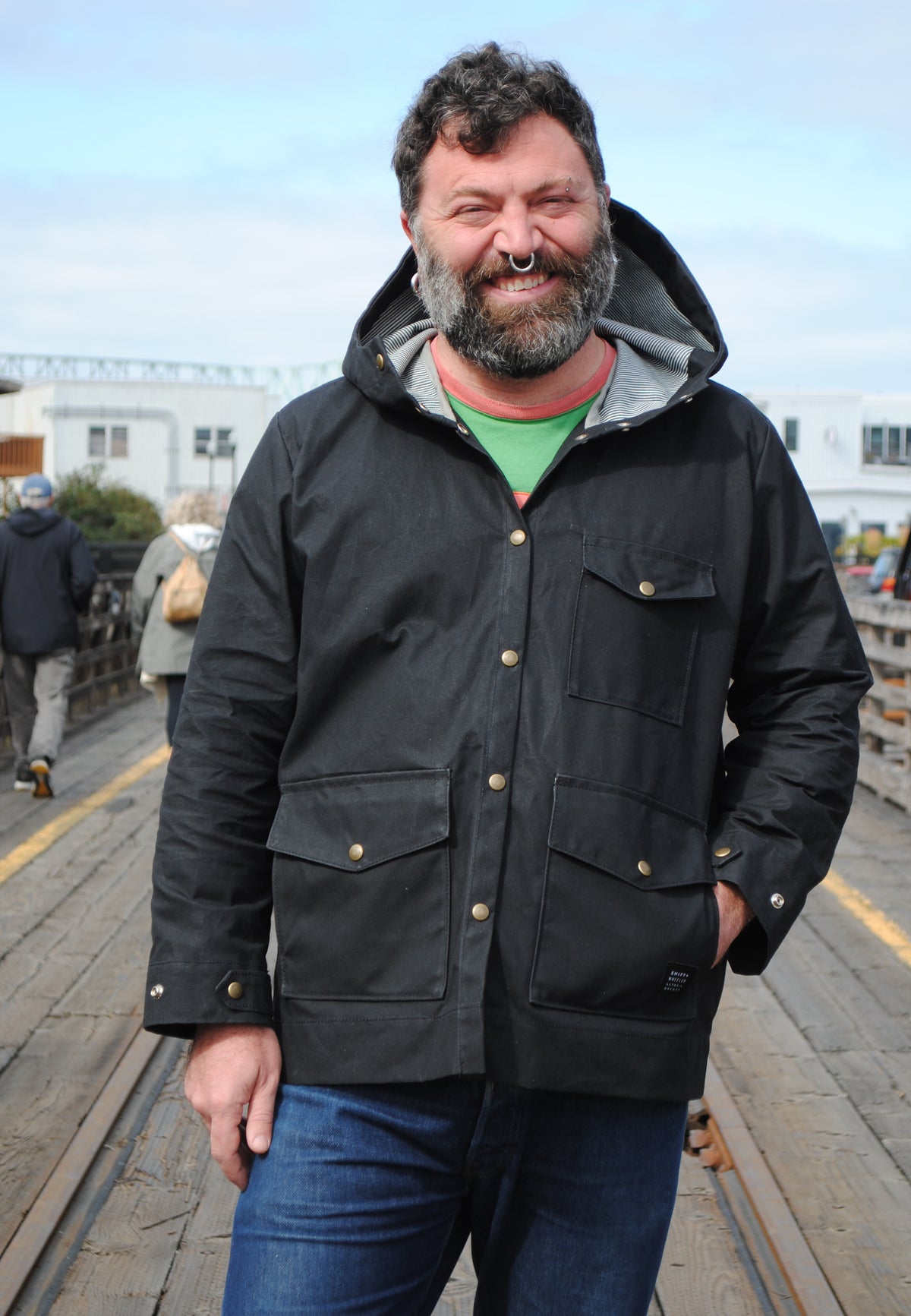 Model smiling while wearing black waxed canvas rain jacket