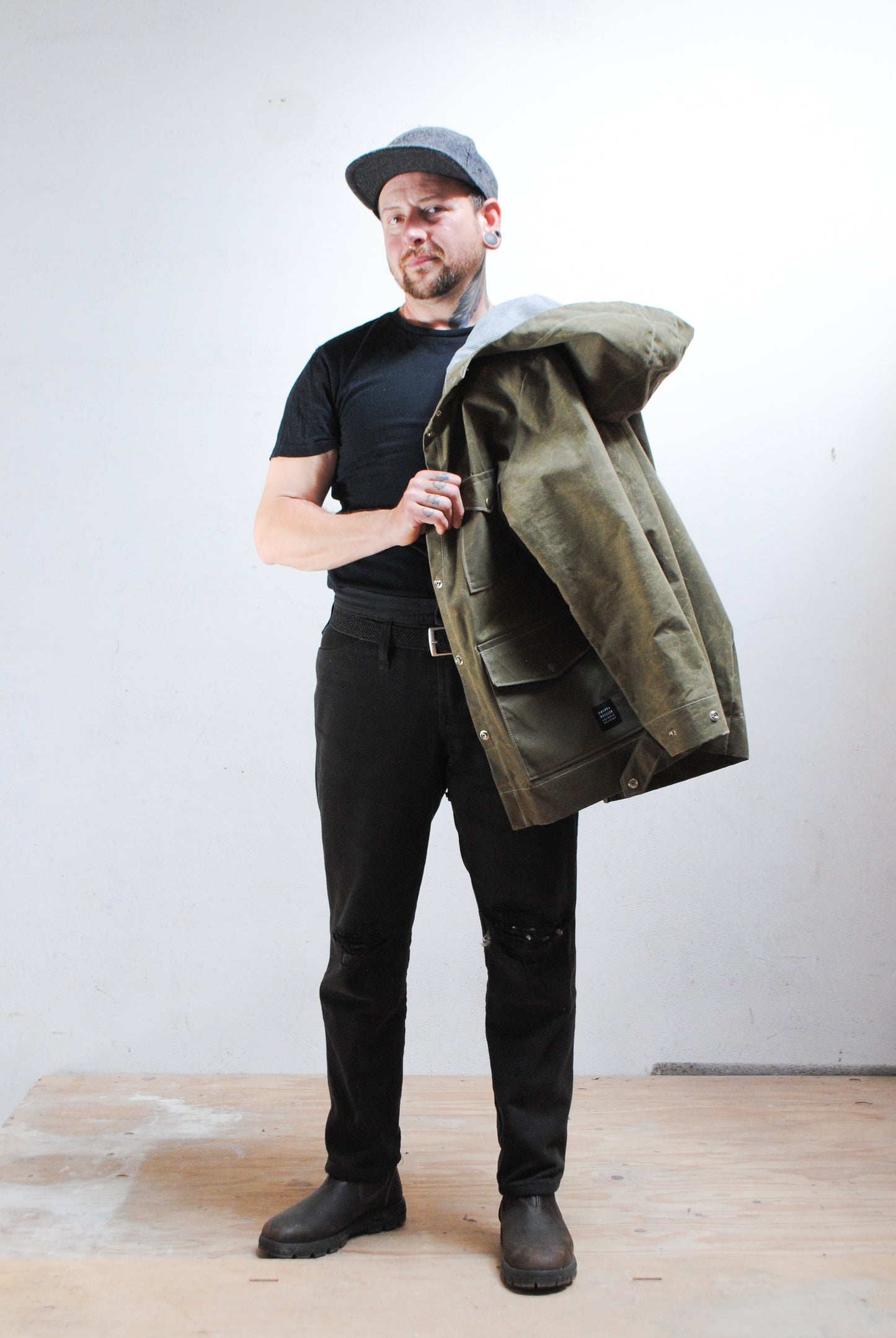 Man wearing a green jacket over a black shirt with a plain background