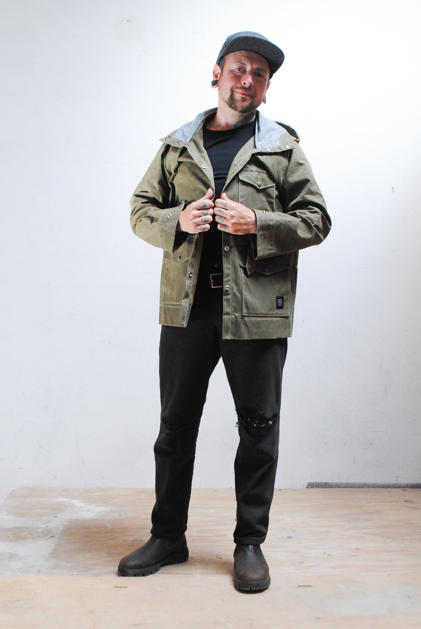 Man wearing a green jacket and black pants against a white background