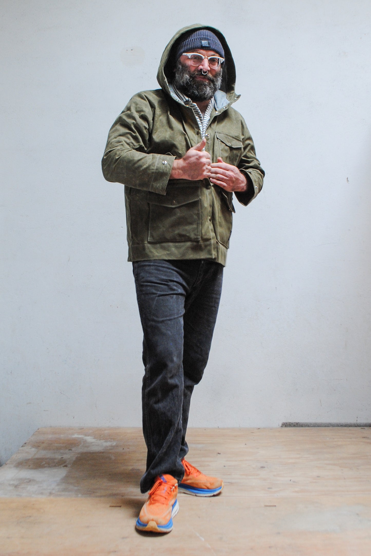 Olive waxed canvas rain jacket features sturdy snaps as a closure.