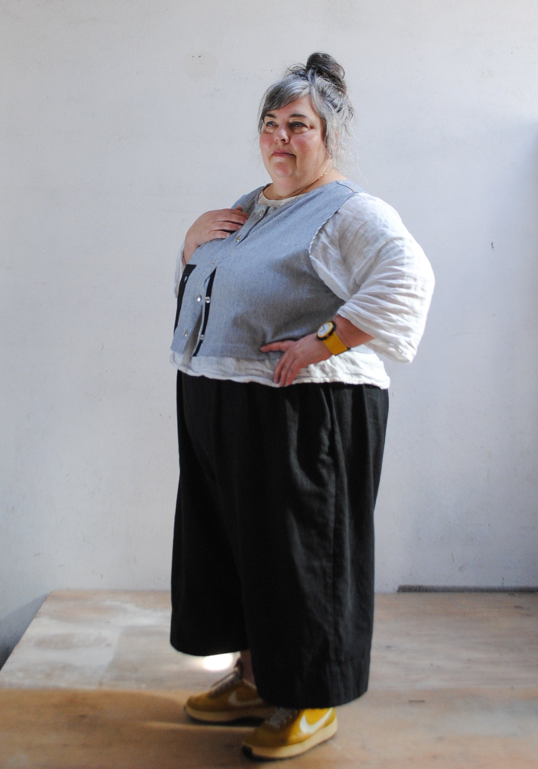 3/4 view of work vest over linen pants and shirt. 