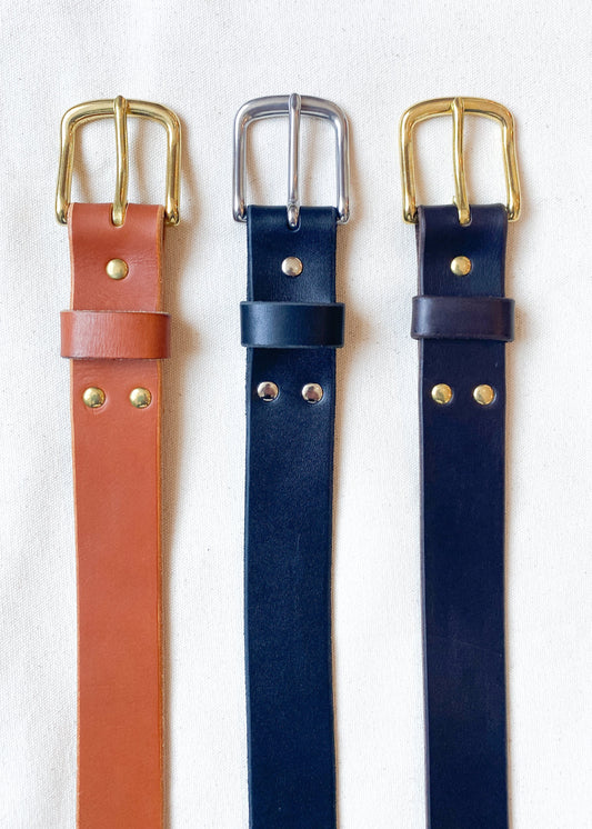 Leather belt in tan with brass, black with silver, and dark brown and brass. 