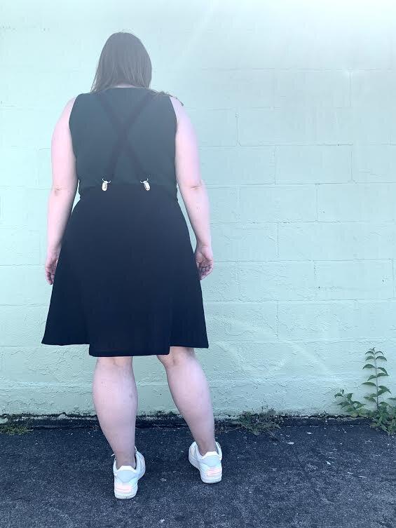 Model showing back view of black linen suspender dress.