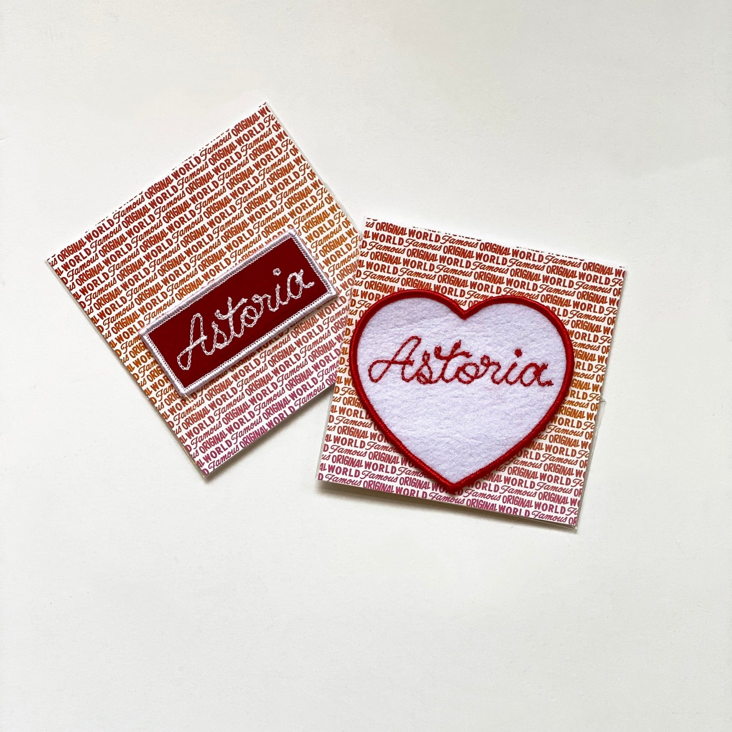 Handmade, custom "Astoria" heart in white felt with red embroidery and "Astoria" rectangle red felt patch with white embroidery, mounted on World Famous Original packaging. 