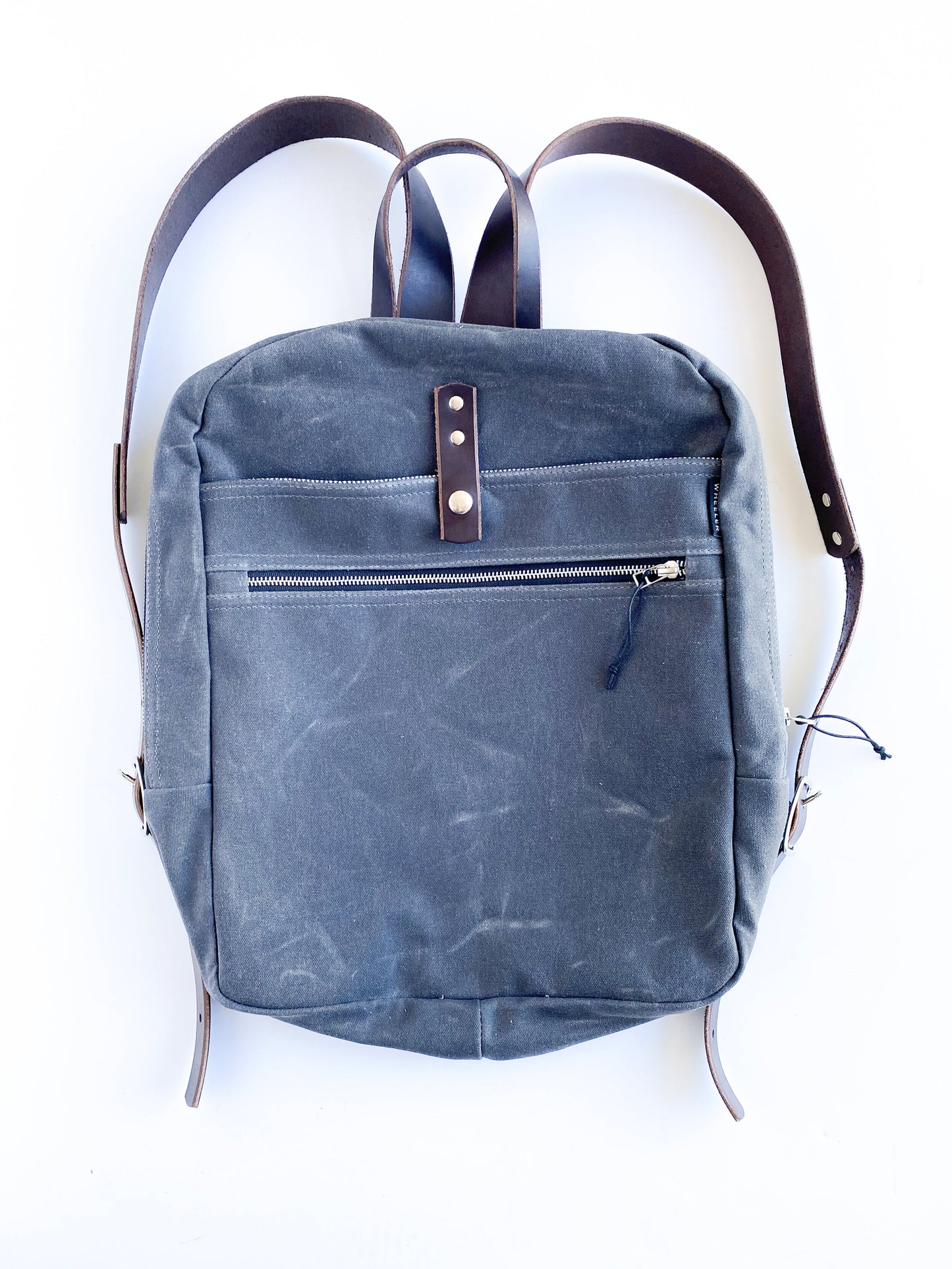 Slate, waxed cotton canvas backpack with brown leather straps.