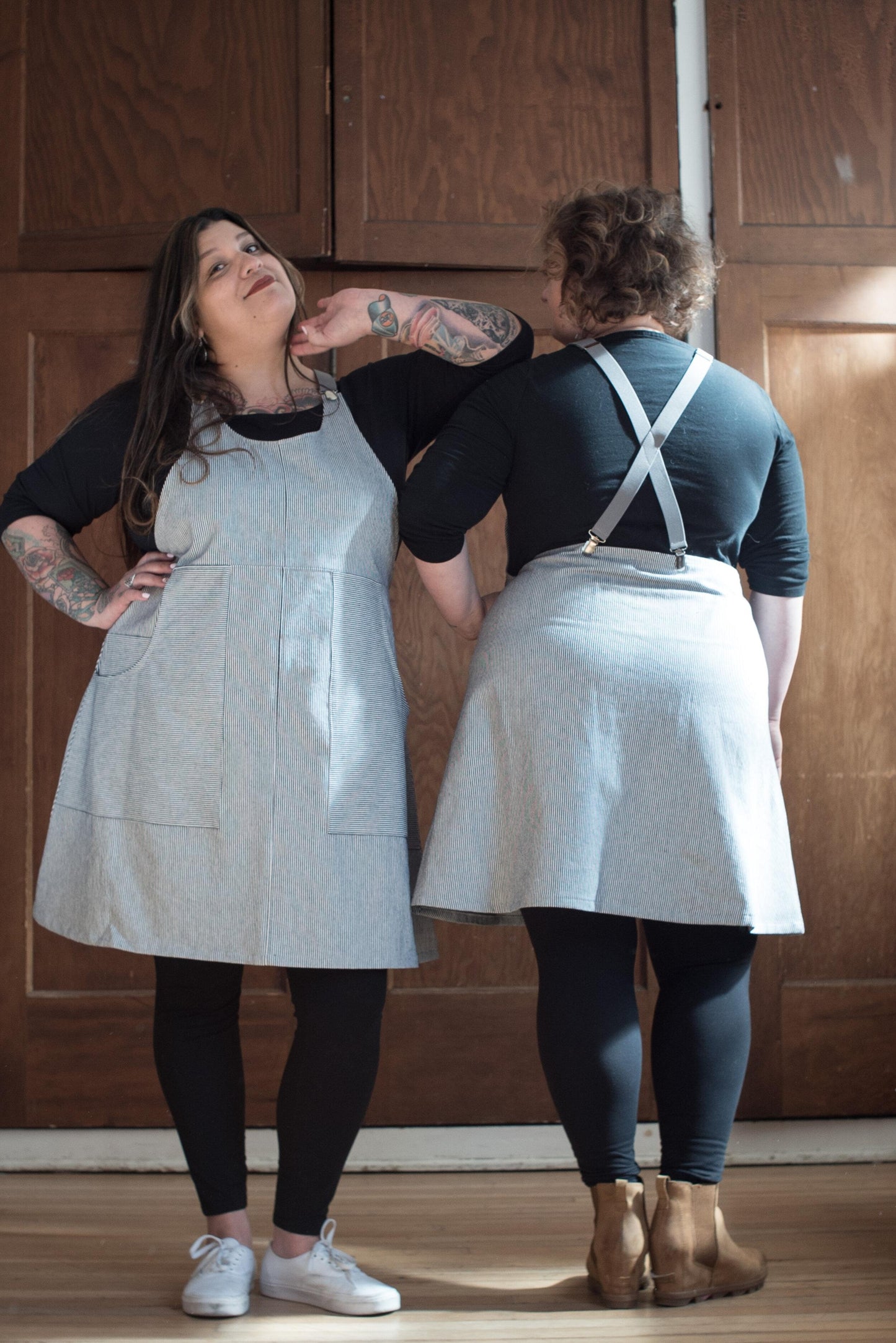 Two models one showing the front and one showing the back of the Railroad Stripe Suspender Dress. 