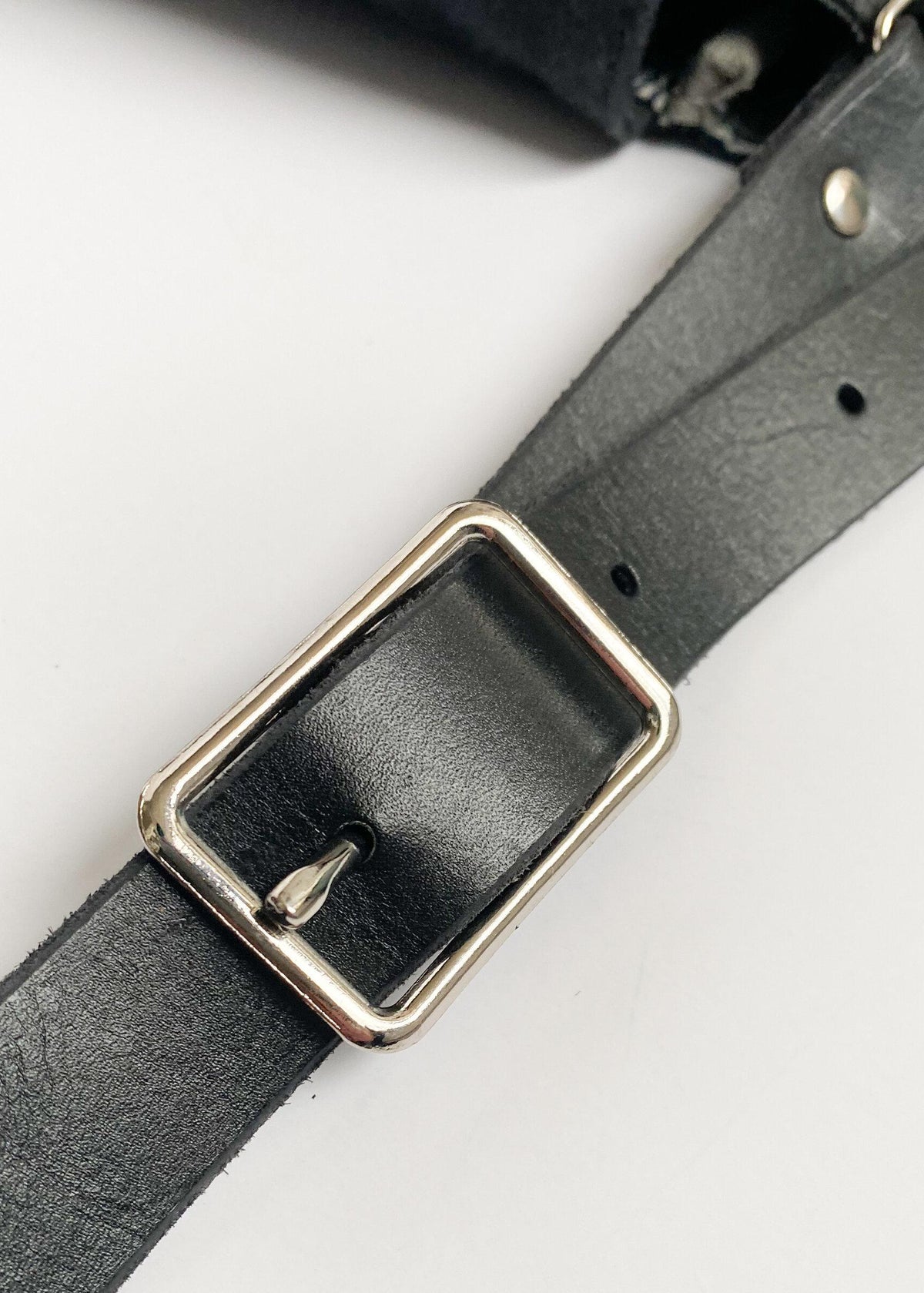 Black leather strap and nickel buckle detail. 