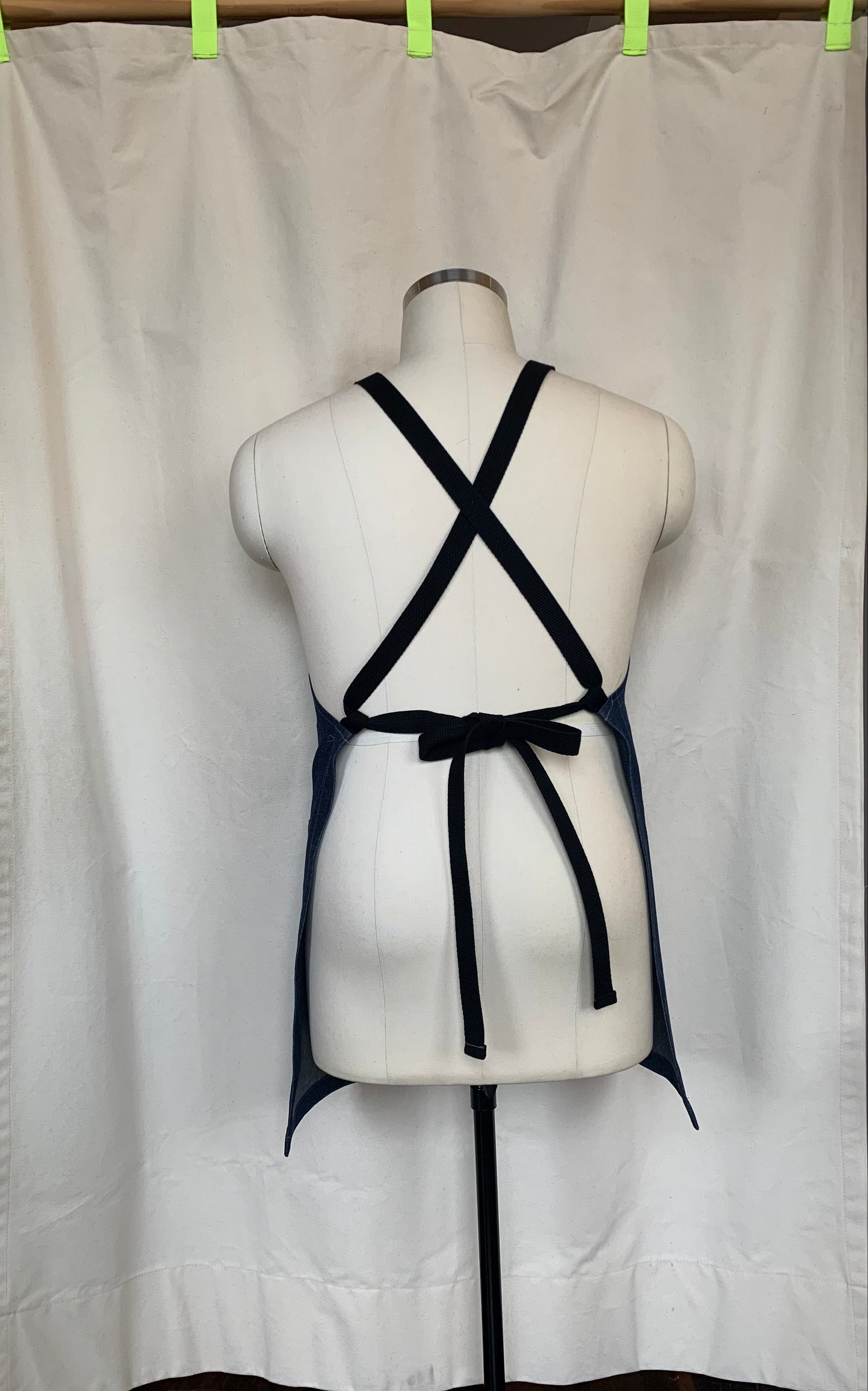 Back detail denim cross back apron shown on mannequin. 