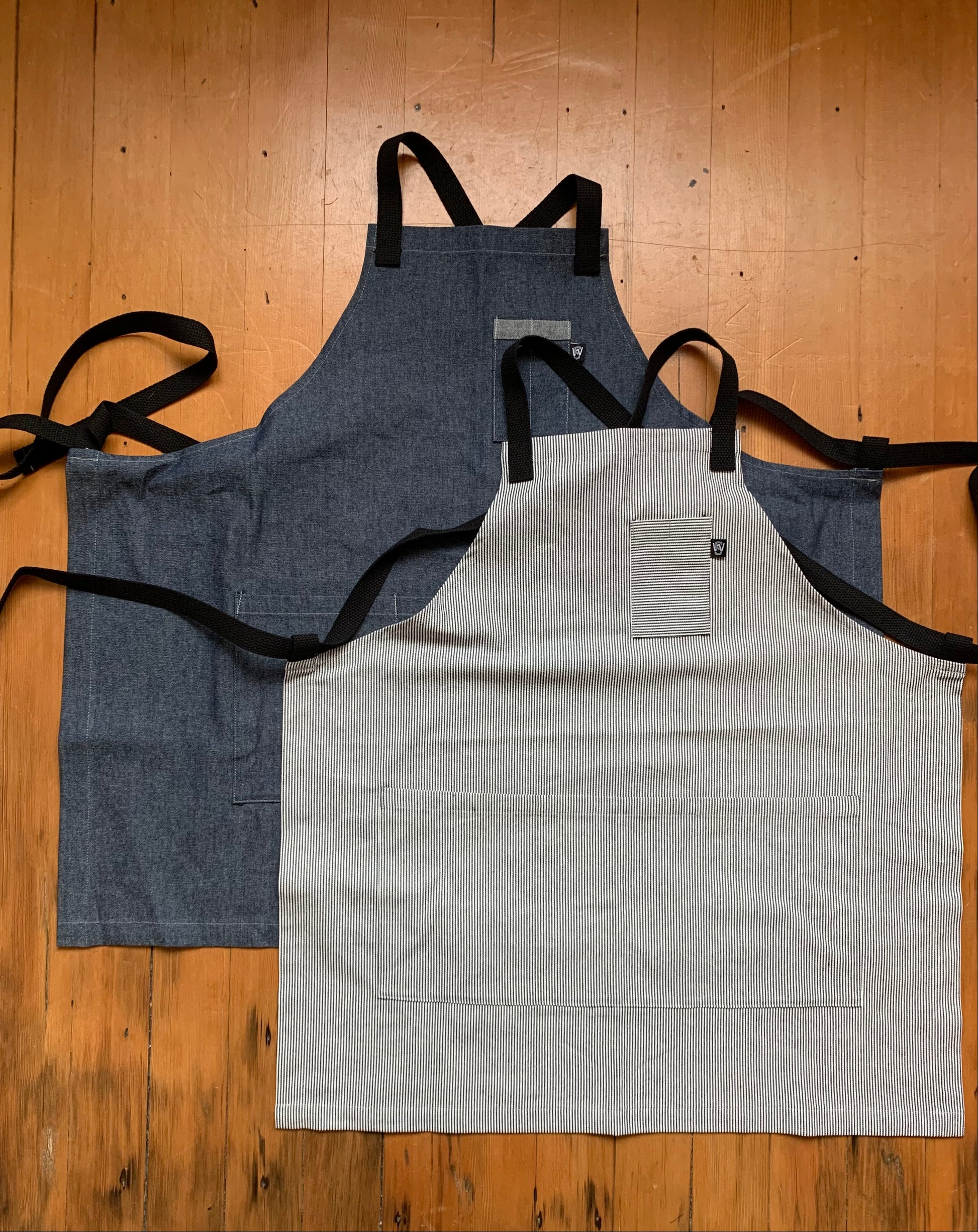 Cotton denim crossback apron shown in denim and railroad stripe. 