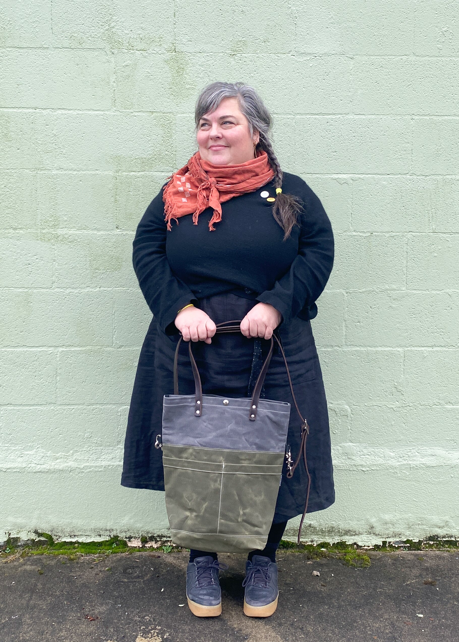 Model holding olive and slate convertible tote with smaller handles. 