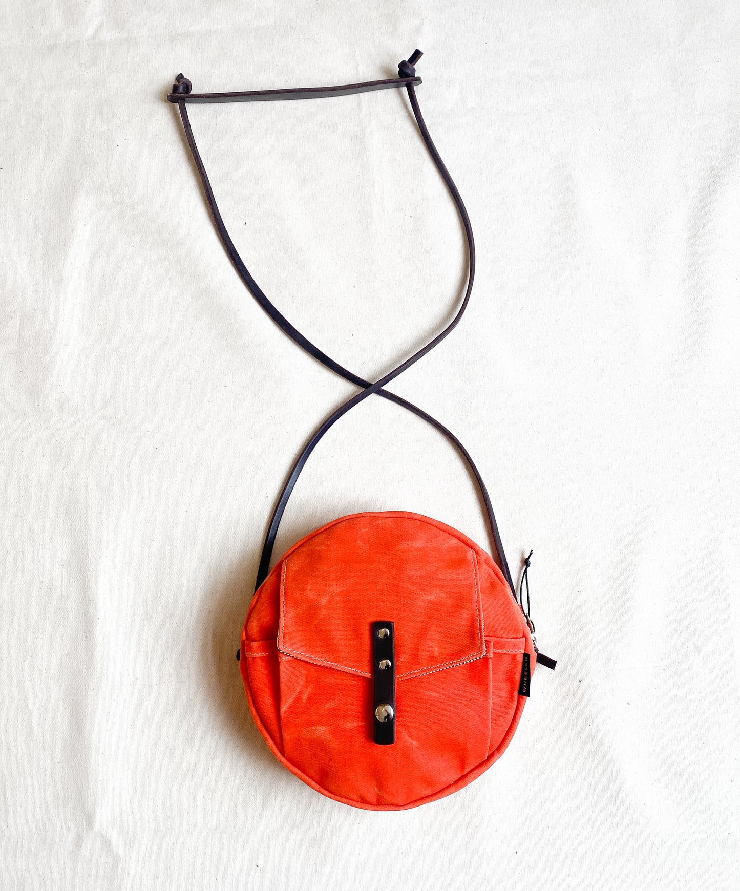 Circle bag with leather straps in orange.