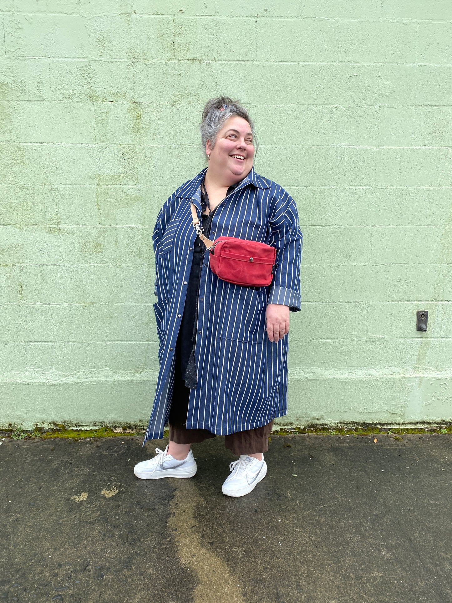 Waxed Canvas cross body bag with leather strap.  Model is wearing Shift Clown Coat.