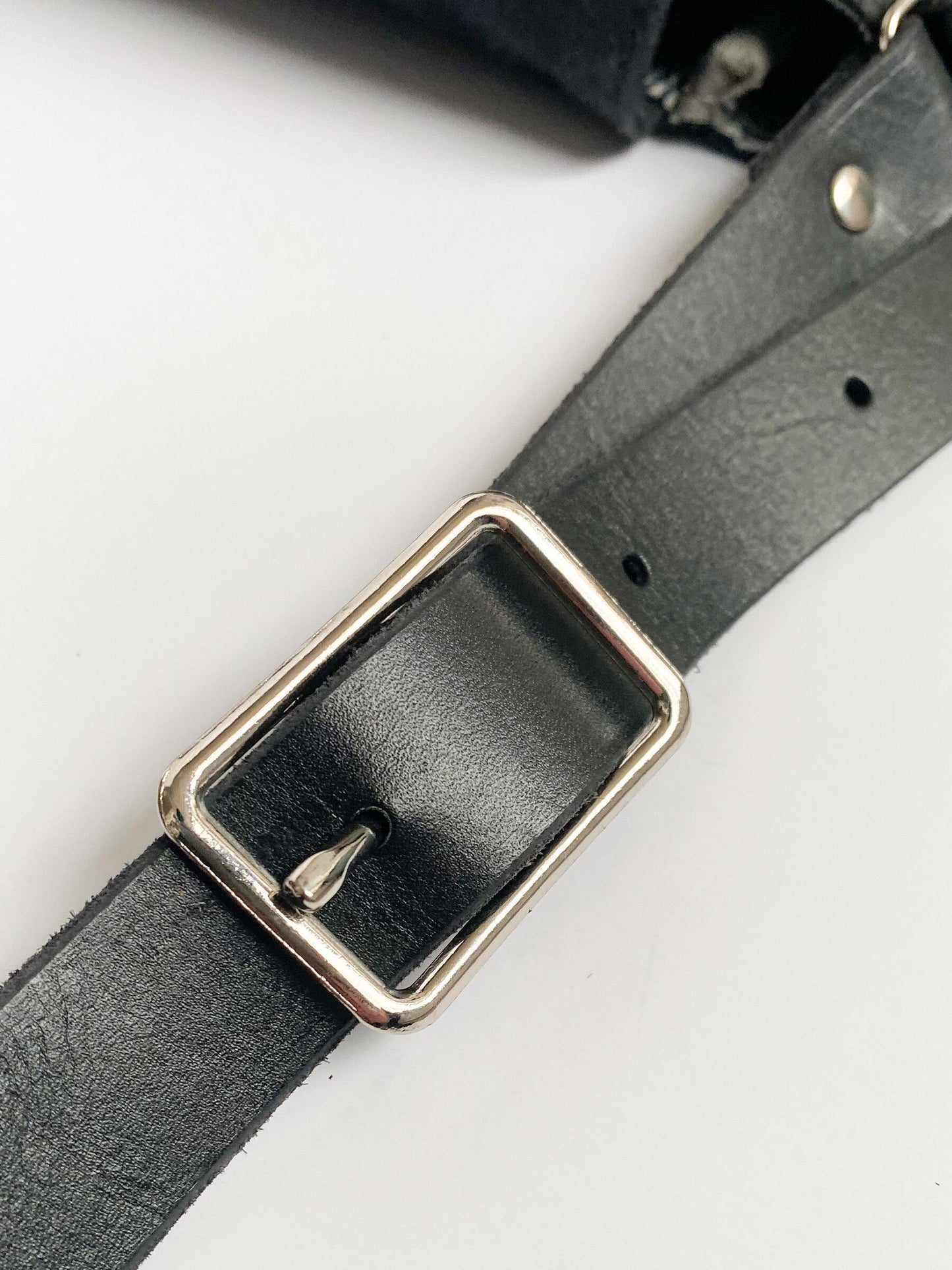 Black leather strap and nickel buckle detail. 