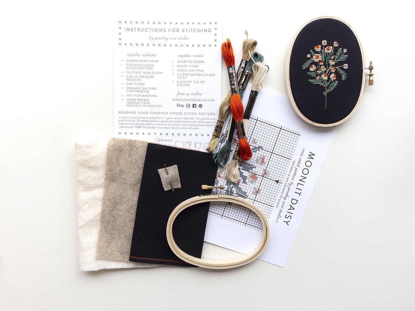 Contents of Moonlit Daisy Cross Stitch Kit: Embroidery thread, hoop, needles, pattern, directions, felt backing, and organic batting.