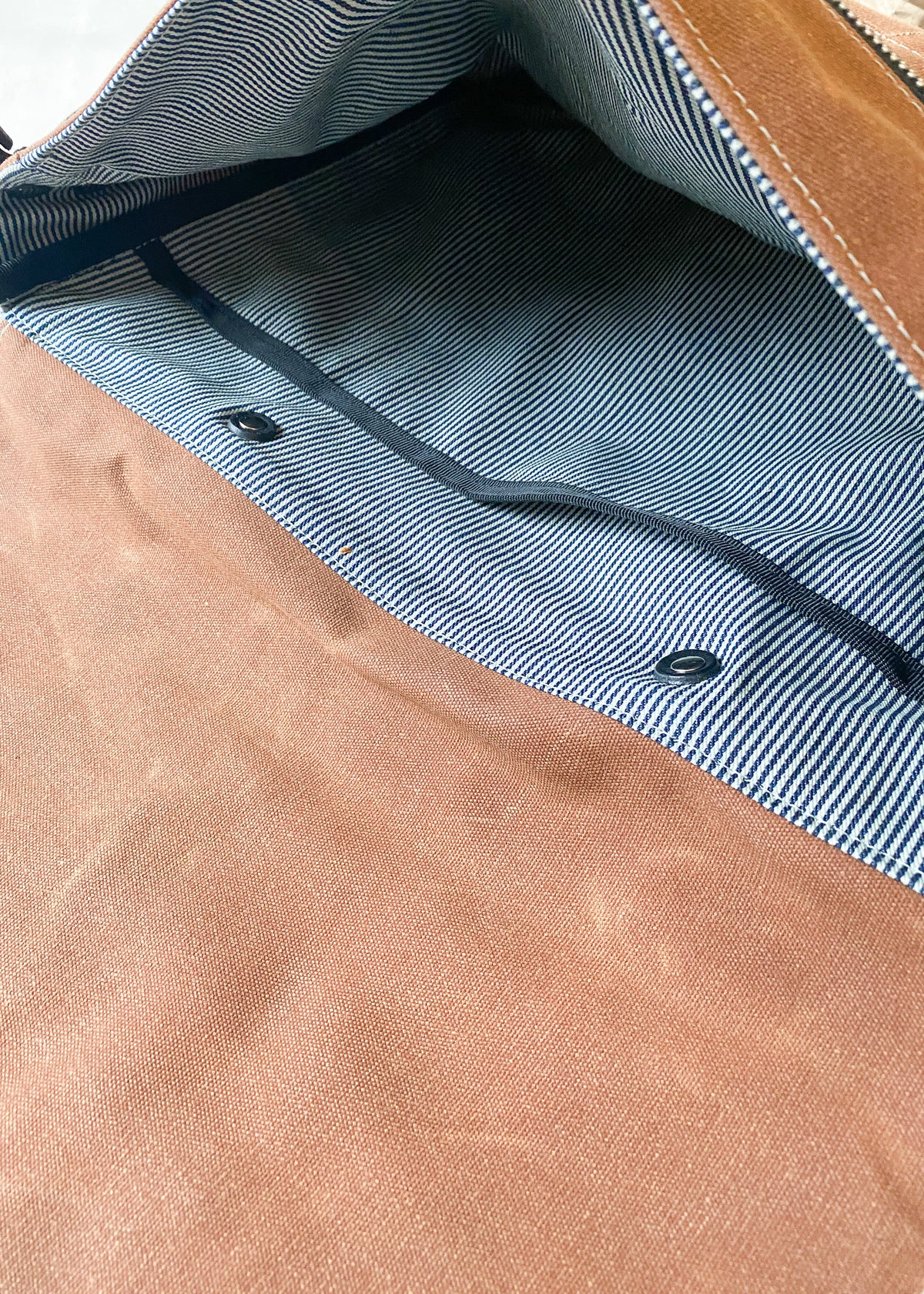 Close up view of inside of brown Shift + Wheeler waxed canvas messenger bag